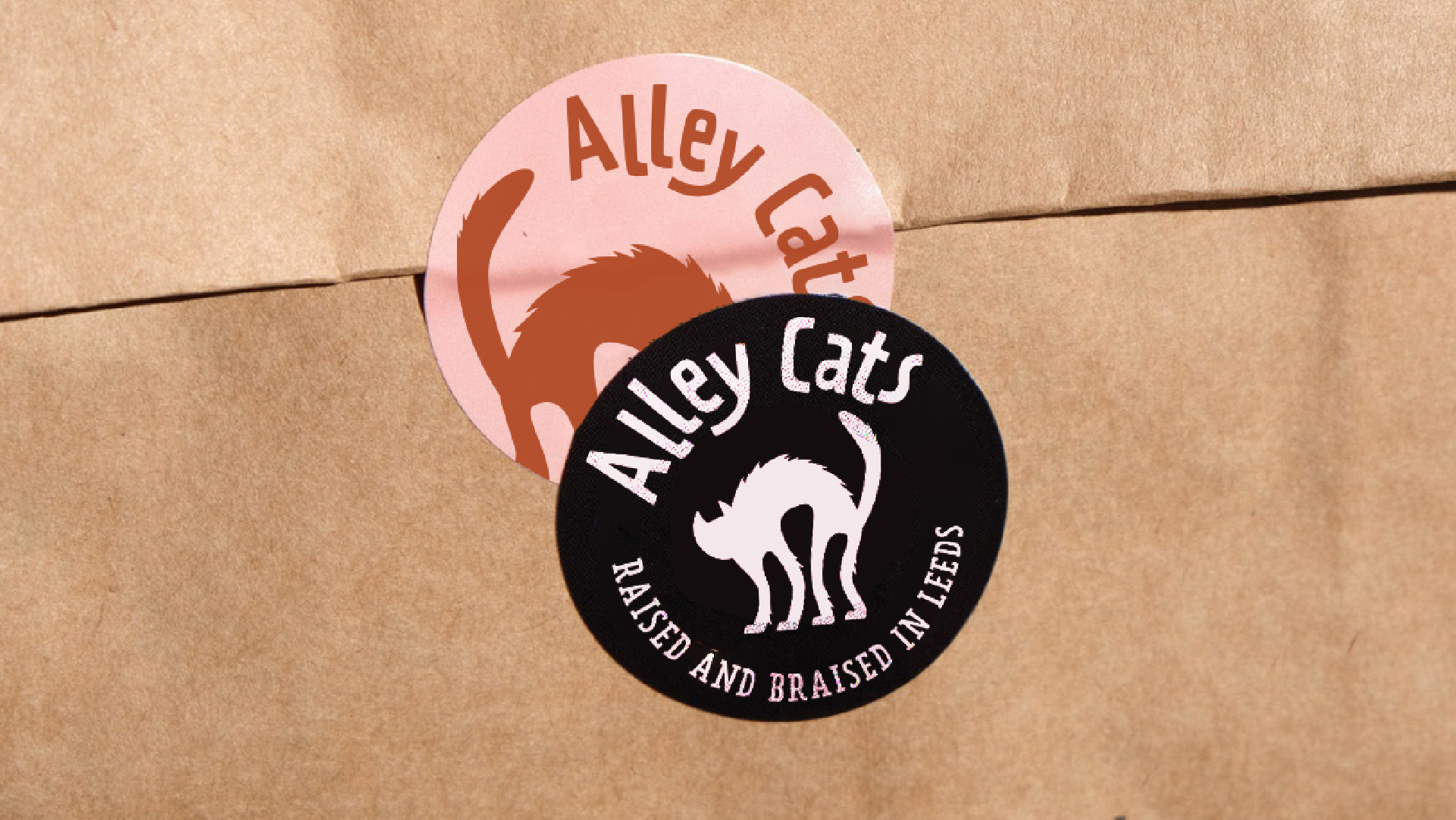 alley cats logo printed on stickers that are stuck on a paper carry-on bag